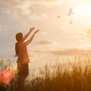 Freedom concept: Silhouette woman hand broken chains and praying against sunset.