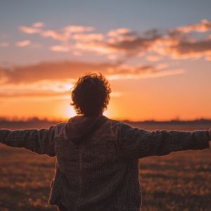 Discovering inner joy Young man in a vast field arms open to the warm sunrise Mind body and spirit idea